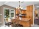 A kitchen island with wood cabinets, granite countertop, and chairs looking out to the backyard at 7164 Moss Point Dr, Charlotte, NC 28277