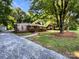 Charming brick home featuring a covered front porch, gravel driveway, and mature trees at 7812 Old Concord Rd, Salisbury, NC 28146