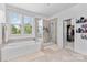 Bright bathroom with a soaking tub under a large window and glass-enclosed shower with tiled walls at 9801 Blackbird Hill Ln, Mint Hill, NC 28227