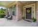 Inviting front porch with black door, colorful floral wreath, and seating for guests and enjoying the outdoors at 9801 Blackbird Hill Ln, Mint Hill, NC 28227