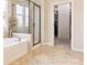 Bright bathroom showcasing a glass-enclosed shower, soaking tub, and entrance to the walk-in closet with custom shelving at 1009 Hampton Grove Rd, Waxhaw, NC 28173