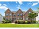 Beautiful brick home with lush landscaping and green shutters under a bright blue sky at 1009 Murandy Ln, Matthews, NC 28104