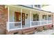 Inviting front porch with a stained wood front door with sidelights and hanging floral arrangements and painted wood railing at 110 Club Dr, Mooresville, NC 28115