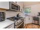 Close-up of the renovated kitchen featuring stainless steel stove, microwave, subway tile backsplash, and granite countertops at 110 Club Dr, Mooresville, NC 28115