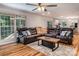 Bright living room boasts a brown leather sectional, wood floors, modern ceiling fan and open access to the kitchen at 110 Club Dr, Mooresville, NC 28115