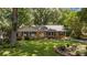 Charming brick ranch home with lush landscaping, mature trees, and a welcoming yellow front door at 11329 Torino Rd, Matthews, NC 28105