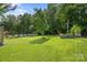 Spacious backyard with lush lawn, bordered by mature trees and a garden, ideal for outdoor activities at 129 Nims Spring Dr, Fort Mill, SC 29715