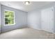 Clean bedroom featuring neutral walls, plush carpeting, a bright window, and a closet door at 129 Nims Spring Dr, Fort Mill, SC 29715