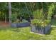 Close-up view of raised garden beds with healthy vegetation, framed by a black fence and trees at 129 Nims Spring Dr, Fort Mill, SC 29715