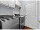 Modern laundry room boasts gray front-loading washer and dryer with overhead cabinets at 129 Nims Spring Dr, Fort Mill, SC 29715