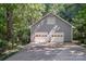 Gray home featuring an attached two-car garage with white doors surrounded by lush trees and foliage at 140 Rustic Way Ln, Mooresville, NC 28117