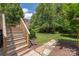 A well maintained backyard offers a serene retreat with lush greenery, a stone pathway, and multi-level wooden staircase at 14103 Hiawatha Ct, Huntersville, NC 28078