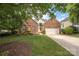 Charming brick home with mature trees, landscaped yard, and a two-car garage on a sunny day at 14103 Hiawatha Ct, Huntersville, NC 28078