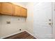 A well-lit laundry room with wood cabinets, wood-look floors and white interior door at 14103 Hiawatha Ct, Huntersville, NC 28078