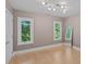Neutral bedroom with hardwood floors, natural light from two windows, and a full-length mirror at 15724 Eagleview Dr, Charlotte, NC 28278