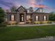 Charming brick home featuring a stone facade entrance, manicured lawn and lush landscaping at 217 Turtleback Rdg, Weddington, NC 28104