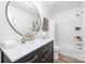 Stylish bathroom featuring a black vanity with gold hardware, a round mirror, and a shower-tub combo at 3100 Hickory Grove Dr, Monroe, NC 28110