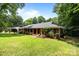 Charming home featuring a brick facade, a well-manicured lawn, mature trees, and covered front porch at 324 Swamp Fox Dr, Fort Mill, SC 29715