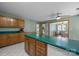 Well-lit kitchen featuring an island, green countertops, light wood cabinets, and access to the sunroom at 324 Swamp Fox Dr, Fort Mill, SC 29715