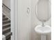 Bright half bathroom features a pedestal sink, an oval mirror, and a carpeted stairway at 3734 Stanley Creek Dr, Mount Holly, NC 28120