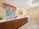 Bright laundry room with ample counter space, wooden cabinets, and a large window overlooking the backyard at 394 E Goldmine Rd, Wadesboro, NC 28170