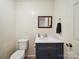 This updated powder room features a white countertop, navy vanity, paneled walls, and wooden-style vinyl flooring at 394 E Goldmine Rd, Wadesboro, NC 28170