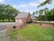 Brick home with detached garage, landscaping, and access to a backyard pool and patio at 394 E Goldmine Rd, Wadesboro, NC 28170