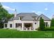 Spacious backyard with a patio, grill, lush green lawn, and a luxurious white brick home at 4714 Ockley Manor Ln, Charlotte, NC 28226