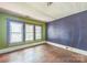 Bedroom with blue accent wall, wood floor and three double hung windows at 537 N Main St, Mooresville, NC 28115