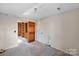 Empty room featuring neutral walls and carpet, with an open doorway to wood-paneled storage shelving at 6017 Millbury Ct, Charlotte, NC 28211