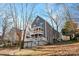 Gray two-story home featuring a double decker porch, set on a gently sloped lot with mature trees at 6017 Millbury Ct, Charlotte, NC 28211