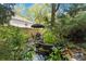 Landscaped backyard oasis with a serene pond, seating area, and lush greenery providing a tranquil retreat at 6921 Thermal Rd, Charlotte, NC 28211