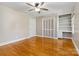 A bedroom with hardwood floors, light gray walls, a ceiling fan, a closet, built-in shelves, and a desk at 6921 Thermal Rd, Charlotte, NC 28211