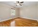 A bright bedroom with hardwood floors, light gray walls, a ceiling fan, and a large window at 6921 Thermal Rd, Charlotte, NC 28211