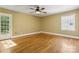 A bright bedroom with hardwood floors, tan walls, white trim, a ceiling fan, and a glass door to the outside at 6921 Thermal Rd, Charlotte, NC 28211
