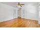 A bright, large bedroom with hardwood floors, white walls, a ceiling fan, two closets, and a window at 6921 Thermal Rd, Charlotte, NC 28211