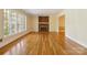 Bright living room featuring gleaming hardwood floors, large windows, and a cozy brick fireplace with white mantel at 6921 Thermal Rd, Charlotte, NC 28211