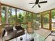 Inviting screened porch features a ceiling fan, wicker furniture, an outdoor grill, and wooded backyard views at 705 Torrey Pines Ln, Fort Mill, SC 29715