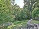 Serene backyard featuring a grassy slope with stone steps and a view of the surrounding woods at 7309 Rock Hampton Ct, Harrisburg, NC 28075