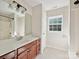 Well-lit bathroom featuring a classic vanity with storage and a shower/tub combo, offering a functional design at 7309 Rock Hampton Ct, Harrisburg, NC 28075