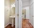 Elegant powder room with a pedestal sink, stylish mirror, hardwood floors, and doorway to laundry room for added convenience at 7309 Rock Hampton Ct, Harrisburg, NC 28075