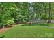 Spacious backyard featuring a fire pit area, surrounded by mature trees and lush green grass at 811 Ashmeade Rd, Charlotte, NC 28211