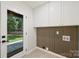 Clean laundry room with upper cabinets, unique slat wall, and door to the backyard at 811 Ashmeade Rd, Charlotte, NC 28211