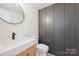Modern powder room featuring a floating vanity, elegant mirror and stylish paneling at 811 Ashmeade Rd, Charlotte, NC 28211