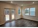 Living room with dark floors, french doors to the backyard, and natural light from three windows at 8231 Annsborough Nw Dr, Concord, NC 28027