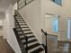 View of the staircase with black railings, dark treads, and view into the living room at 8231 Annsborough Nw Dr, Concord, NC 28027