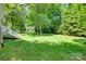 A serene, expansive backyard features lush grass, mature trees, and a glimpse of the home's inviting white staircase at 125 Highland Forest Dr, Clover, SC 29710