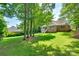Well-maintained backyard featuring a lush lawn and a brick home with a charming white porch and mature shade trees at 125 Highland Forest Dr, Clover, SC 29710