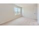 Bright bedroom with neutral carpeting, fresh paint, a window overlooking the neighborhood, and crisp white trim at 144 Astor St, Troutman, NC 28166