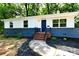 Charming renovated ranch-style home featuring a white exterior with a blue brick foundation and black door at 1513 Greenview Pl, Charlotte, NC 28208